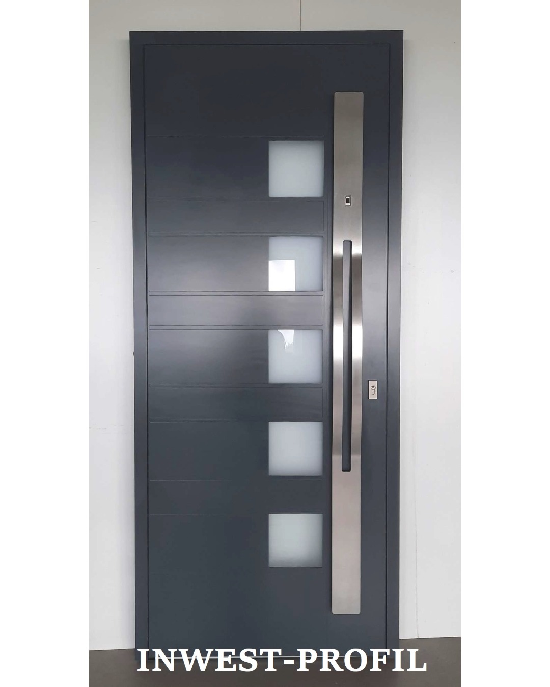 Nowoczesne, antracytowe drzwi wejściowe z czterema kwadratowymi szybami i długim, pionowym, stalowym uchwytem, widoczne na tle białej ściany.