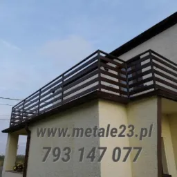 Balkon z prostą, brązową balustradą poziomą, widok z dołu, na ścianie budynku numer telefonu i adres strony internetowej.