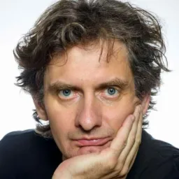 Portret mężczyzny z niebieskimi oczami, opierającego brodę na dłoni, na białym tle.