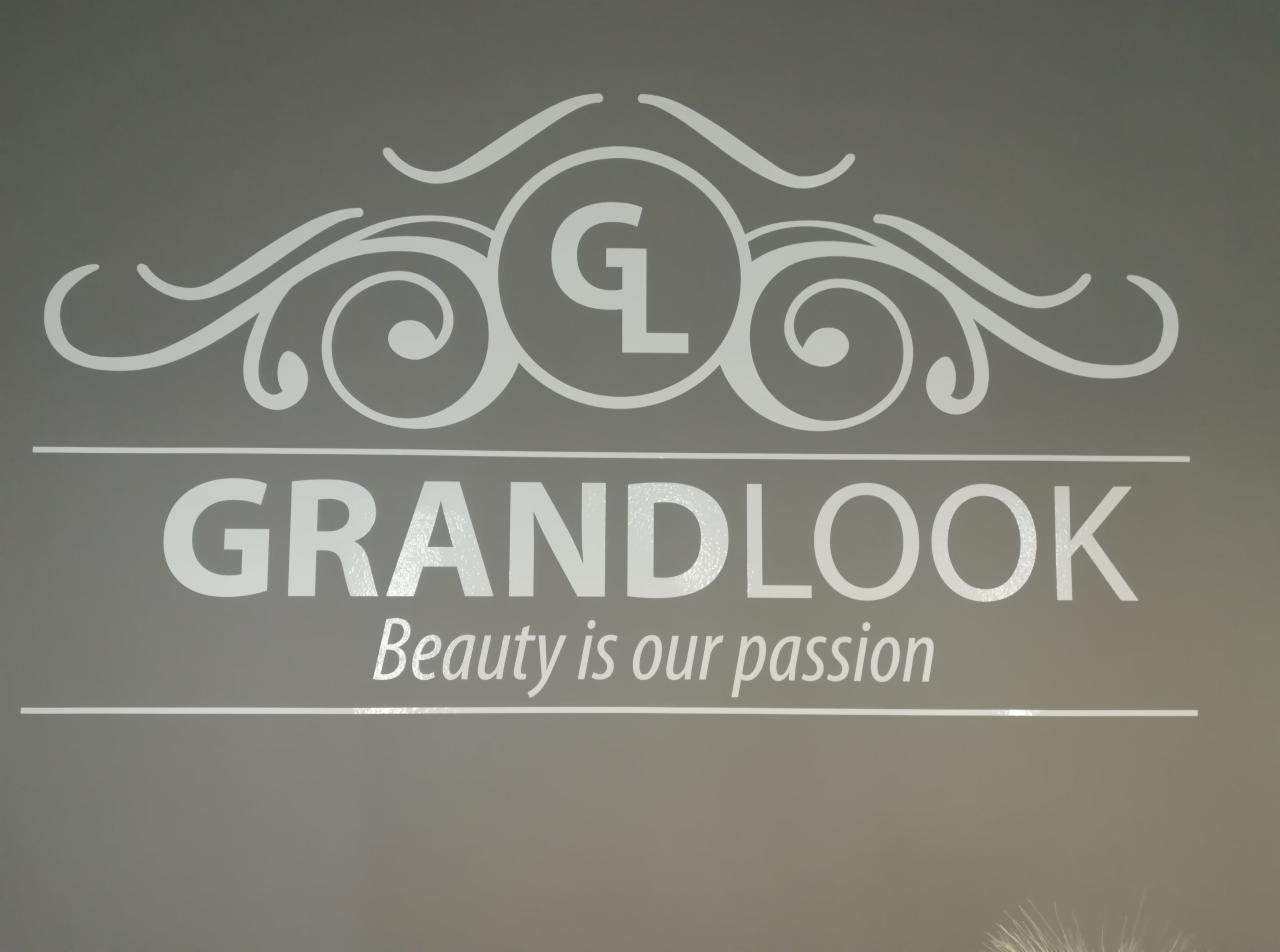 Logo salonu 'GRANDLOOK' z hasłem 'Beauty is our passion' na szarym tle, ozdobne ornamenty.