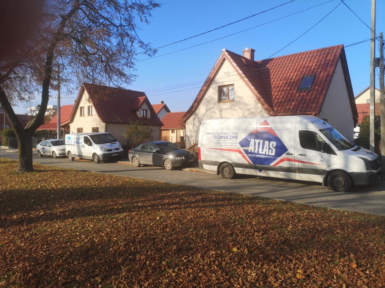 Budynek jednorodzinny z nowym, czerwonym dachem, na pierwszym planie zaparkowany biały samochód dostawczy z logo firmy Atlas.