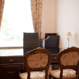 Eleganckie biuro: ciemne drewniane biurko z szufladami, dwa krzesła z wzorzystą tapicerką, lampka nocna na biurku, okno z zasłonami w tle.