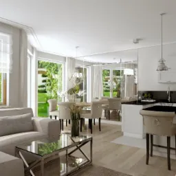 Jasne, przestronne wnętrze: salon z narożną sofą, szklanym stolikiem kawowym, jadalnia z okrągłym stołem i krzesłami z tapicerowanymi oparciami, kuchnia z czarnym blatem i białymi szafkami, duże...