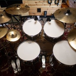 Aroslav Movies - Zestaw perkusyjny z mikrofonami w studiu nagraniowym, widok z góry, dywan z orientalnym wzorem, drewniane ściany.