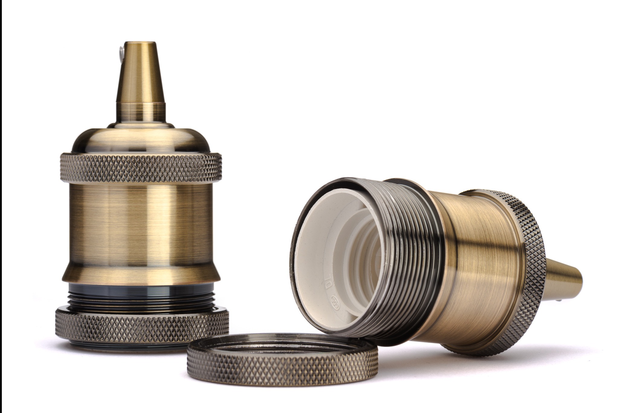 Mosiężna oprawka żarówki E27 w trzech częściach: stojąca, leżąca i pierścień. Detal faktury i gwintu. Produkt na białym tle, oświetlenie studyjne.