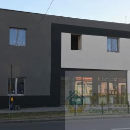 Serwis Budowlany - Dwukondygnacyjny budynek po remoncie elewacji z oknami zabezpieczonymi folią, z częścią w kolorze szarym i białym oddzieloną czarnym pasem.
