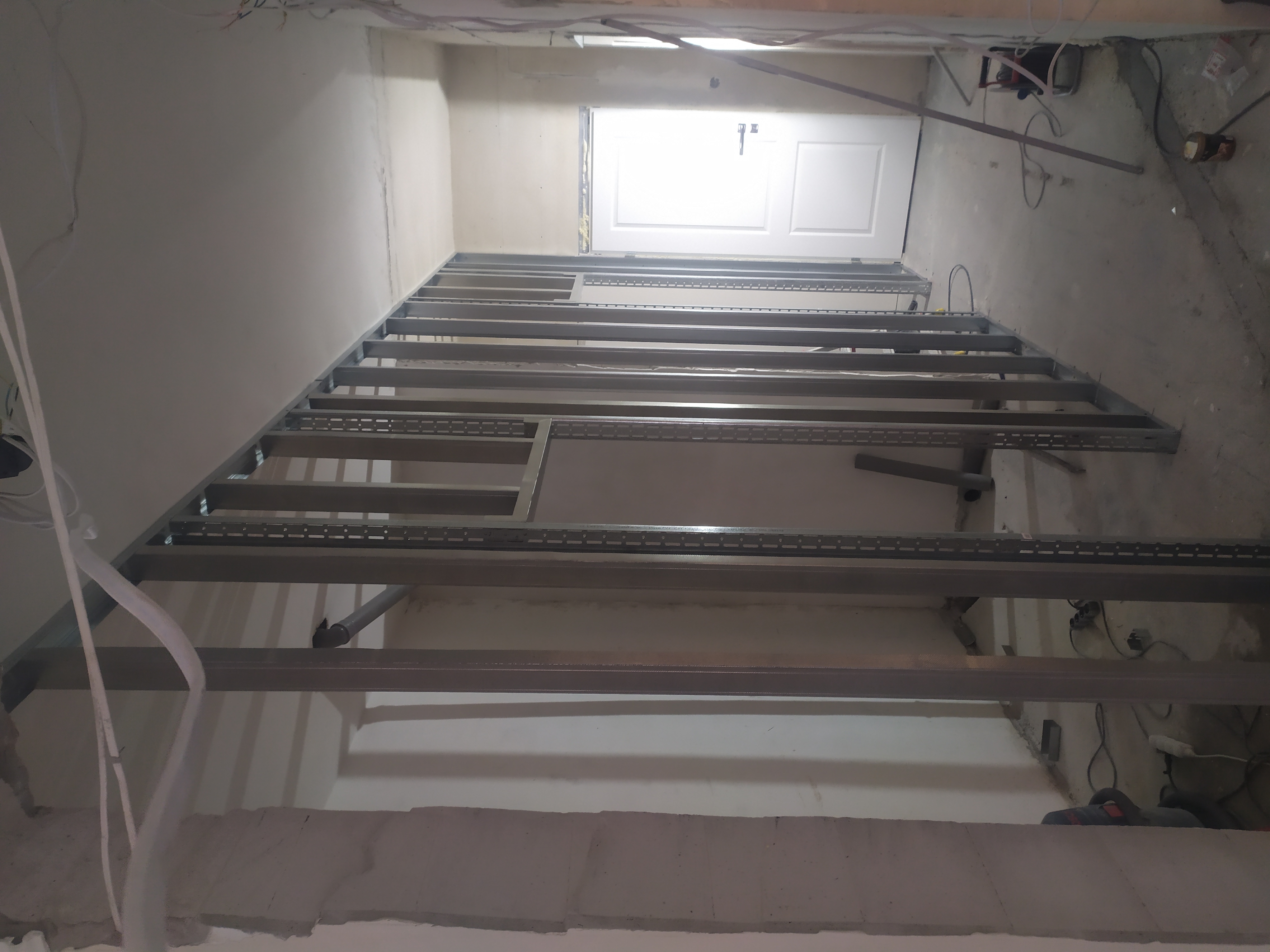 Metalowa konstrukcja szkieletowa pod płytę kartonowo-gipsową, widoczne profile mocowane do sufitu i ścian w surowym stanie, przygotowanie do montażu płyt.