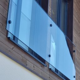 F.P.H.U. EK-GLASS Beata Kocoń - Szklana balustrada balkonowa z mocowaniami punktowymi na tle drewnianej elewacji. Nowoczesny design, czyste linie i przezroczystość szkła.