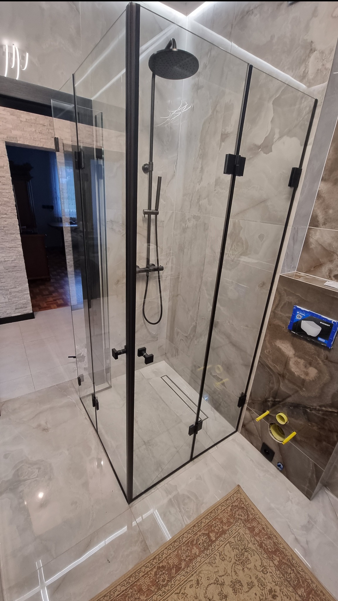 Nowoczesna kabina prysznicowa z czarnymi profilami w Mszanie Dolnej. Szklane ściany, deszczownica i armatura w kolorze czarnym. Widoczny odpływ liniowy w podłodze.