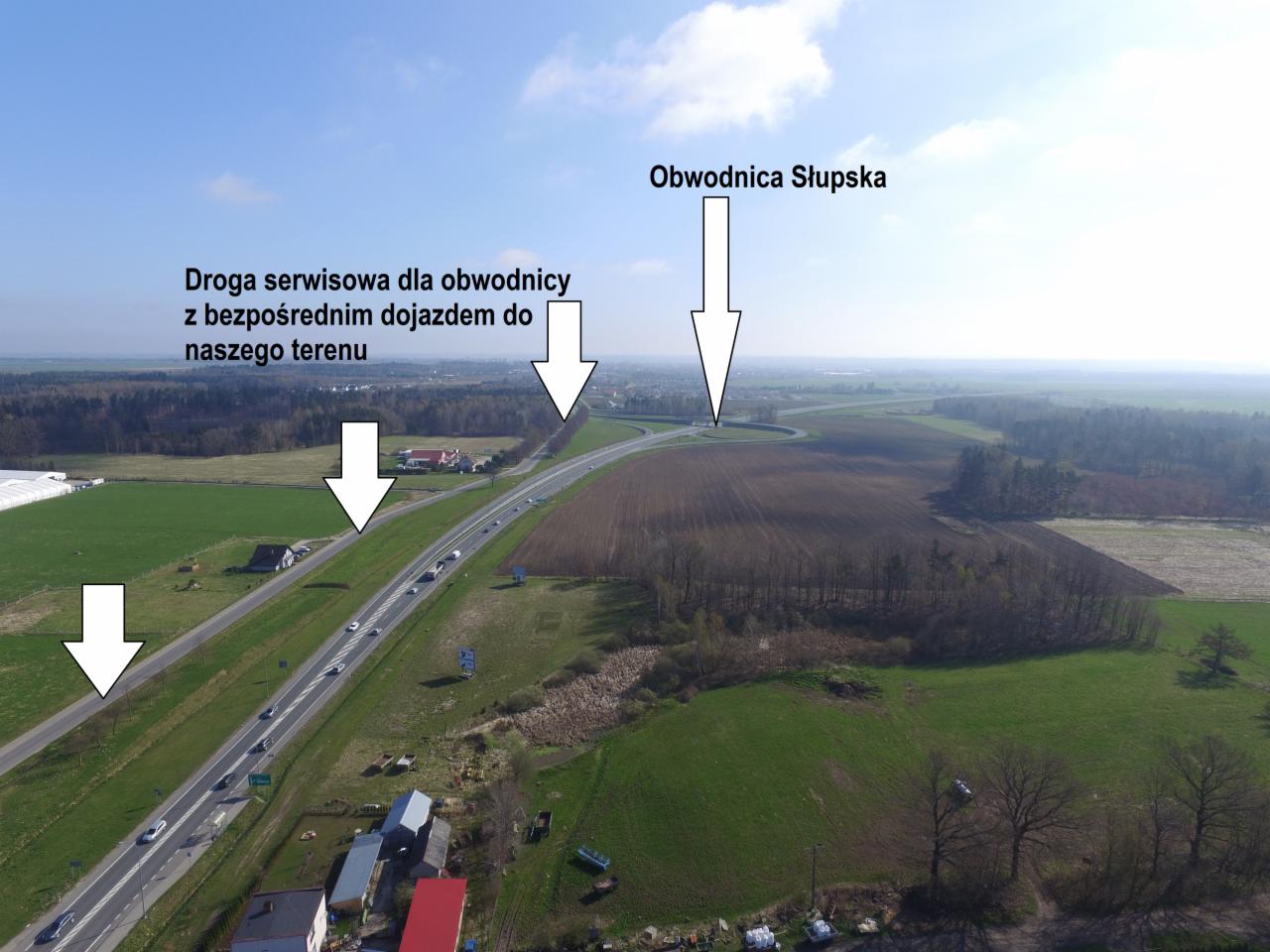 Zdjęcie z drona przedstawiające obwodnicę Słupska, drogę serwisową z bezpośrednim dojazdem do terenu, pola uprawne i zabudowania w oddali.