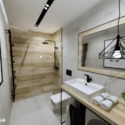 Nowoczesna łazienka z kabiną prysznicową wyłożoną płytkami imitującymi drewno, białą umywalką nablatową, wiszącą toaletą, czarną armaturą i geometryczną lampą wiszącą odbijającą się w lustrze.