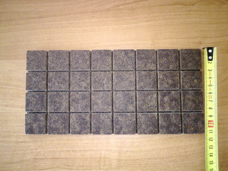 Rząd ułożonych kostek podpałki z płyty pilśniowej miękkiej, obok rozłożona miarka pokazująca wymiary.