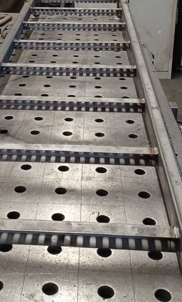 Metalowa konstrukcja stołu spawalniczego z perforowanym blatem i wzmocnieniami, widoczne ślady spawania.