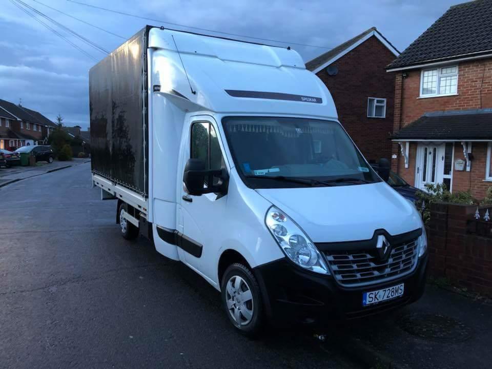 Biały samochód dostawczy Renault Master z plandeką na tle ulicy z domami jednorodzinnymi, widoczna tablica rejestracyjna SK 728MS.