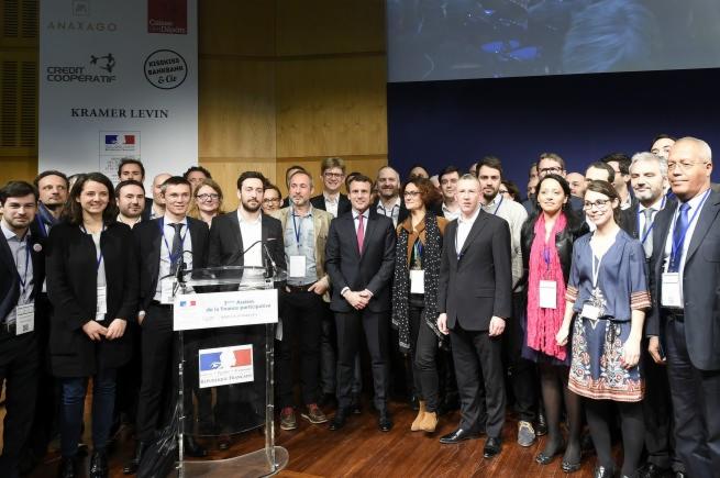 Grupa ludzi pozuje do zdjęcia na tle ścianki z logo firm i instytucji podczas konferencji.