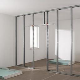 Jeremi Kluczek - Wnętrze w trakcie budowy ściany działowej z metalowych profili i płyt gipsowo-kartonowych, widoczne płyty na podłodze i konstrukcja szkieletowa.