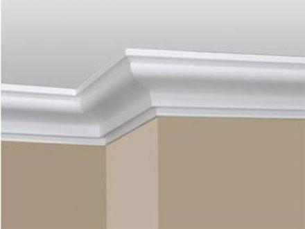 Wykończenie sufitu listwą dekoracyjną w kolorze białym, widok na narożnik ściany pomalowanej na beżowo.