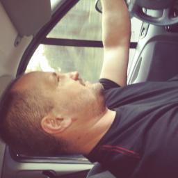 Auto serwis oponex - Mężczyzna śpiący w samochodzie podczas jazdy, widoczna kierownica i fragment okna.