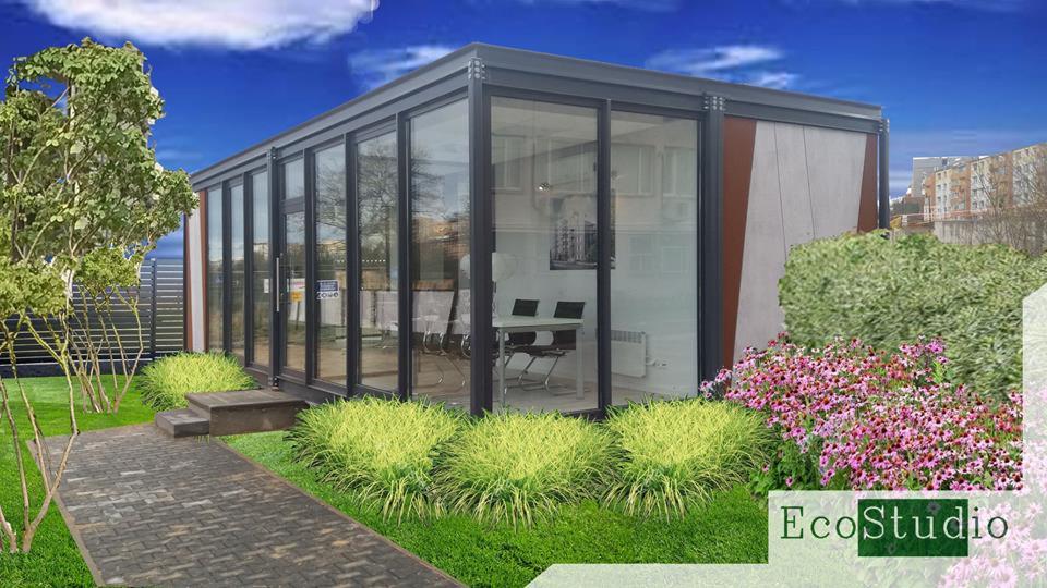 Nowoczesny pawilon ogrodowy z przeszklonymi ścianami, otoczony zielenią, z widocznym wnętrzem biurowym i ścieżką z kostki brukowej prowadzącą do wejścia. W tle zabudowa miejska.