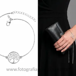 Srebrna bransoletka z motywem drzewa na kobiecej ręce, z czarną sukienką i torebką w tle. Fotografia produktowa biżuterii.