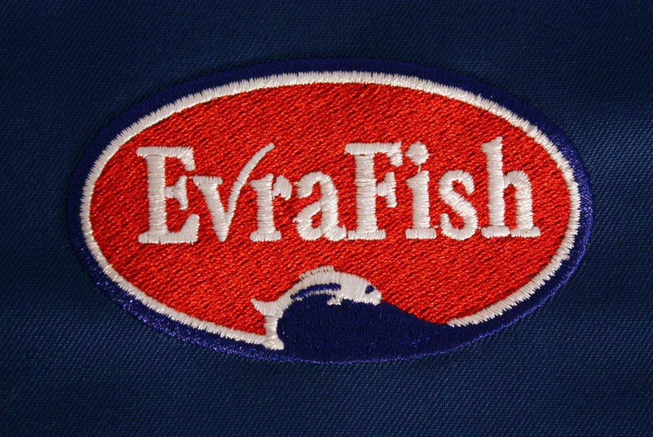 Haftowana naszywka EvraFish na granatowym materiale, przedstawiająca stylizowaną rybę wyskakującą z fali.