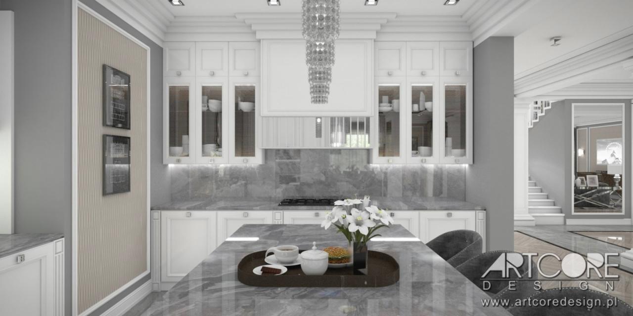 Elegancka kuchnia w odcieniach szarości i bieli z wyspą, na której znajduje się taca z filiżanką, cukiernicą i kanapką, nad wyspą wisi kryształowy żyrandol, w tle widoczne schody i lustro.