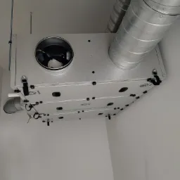 Zamontowany rekuperator z widocznymi przewodami wentylacyjnymi w Ornecie. Srebrny rekuperator podwieszony pod sufitem w jasnym pomieszczeniu.