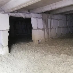 Izolacja pod podłogą, widoczne bloczki fundamentowe i warstwa izolacji z celulozy lub wełny mineralnej.