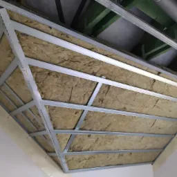 Sufit podwieszany z wełną mineralną w Kłodzku, widoczne metalowe profile konstrukcyjne i izolacja termiczna przed montażem płyt gipsowo-kartonowych.