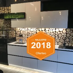 Nowoczesna kuchnia w Warszawie z białymi, lakierowanymi frontami i blatem, dekoracyjnym panelem ściennym z przekrojów drewna oraz czarną armaturą i piekarnikiem.