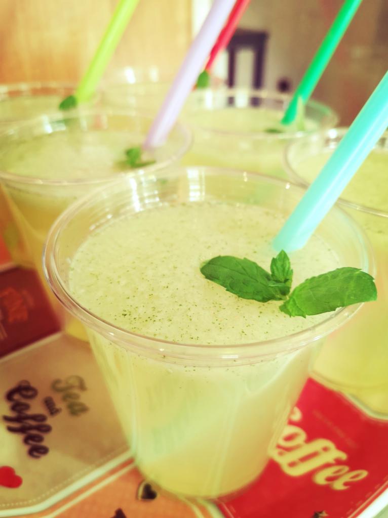 Szklanki z lemoniadą miętową i kolorowymi słomkami, ustawione na serwetkach z motywem kawy i herbaty.