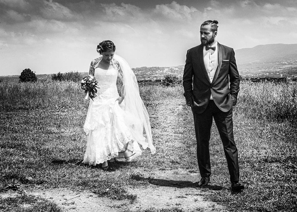 Czarno-biała fotografia plenerowa z Kruszyna Krajeńskiego przedstawiająca parę młodą: pannę młodą w koronkowej sukni i welonie, trzymającą bukiet, oraz pana młodego w garniturze z muszką, stojących...