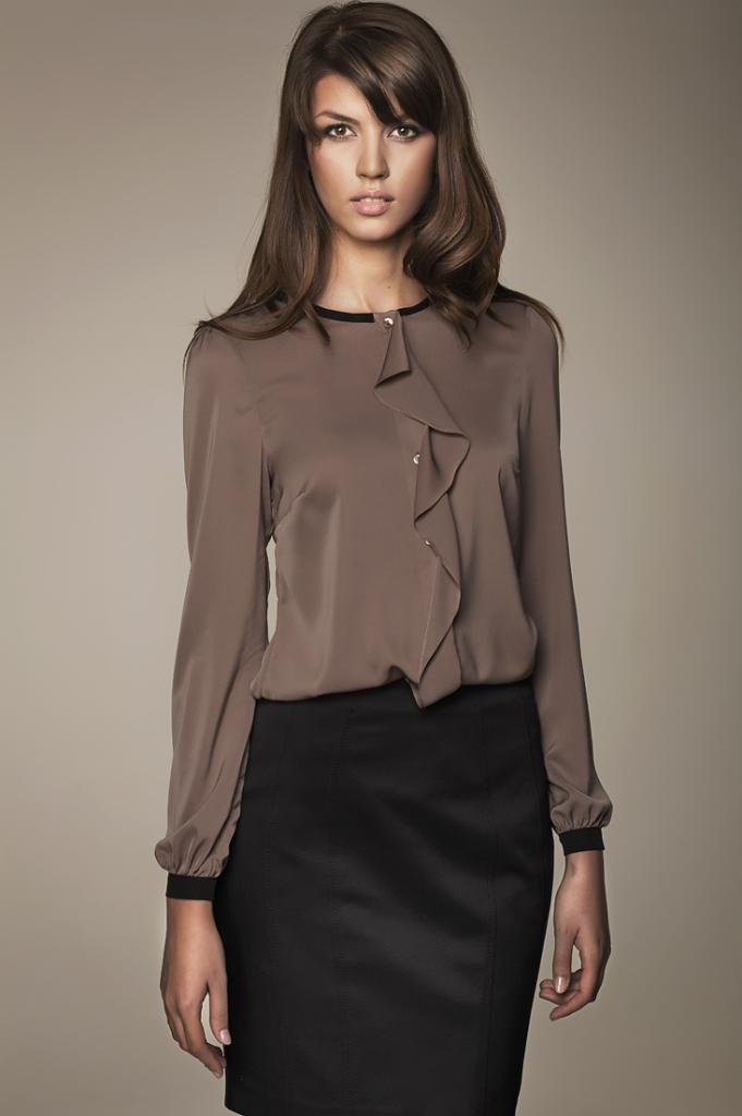 Kobieta prezentuje brązową bluzkę z falbaną i czarną spódnicę ołówkową na neutralnym tle.