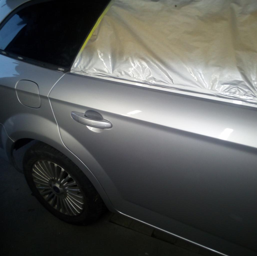 Srebrny samochód z zaklejoną folią ochronną szybą, przygotowywany do lakierowania.