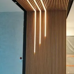 Drewniane lamele na suficie i ścianie z wbudowanym oświetleniem LED, tworzące nowoczesny design wnętrza.