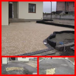 Niedawno ułożona, beżowa kostka brukowa na podjeździe przed domem jednorodzinnym, z czarnym obramowaniem i plastikowymi obrzeżami rabat kwiatowych; widoczne przygotowane podłoże pod dalszą część...