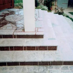 Kamienne schody wejściowe z mozaiką na podłodze w Sobótce, prowadzące do domu z białą kolumną.