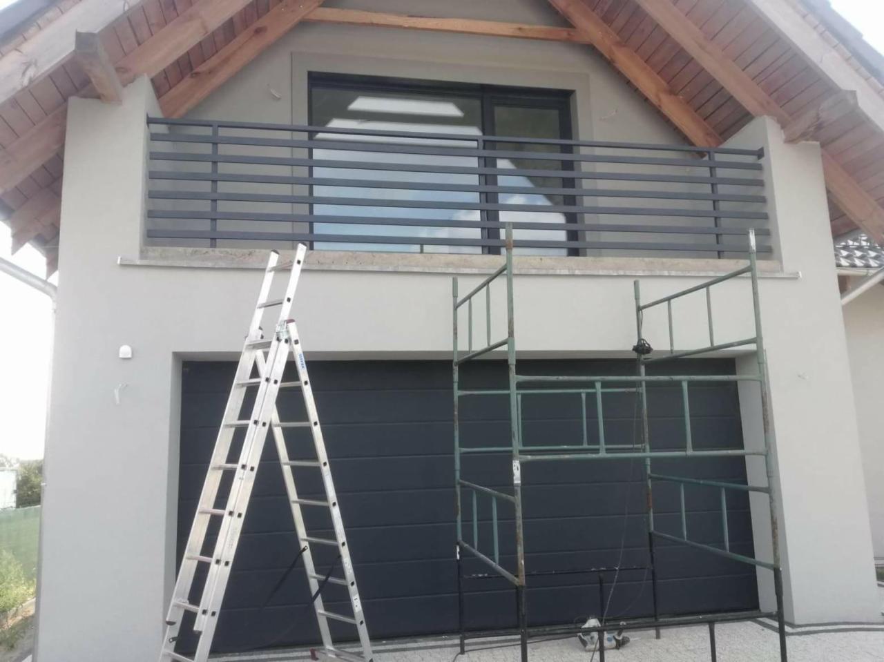 Nowoczesna balustrada balkonowa z metalowych profili zamontowana na budynku, widoczne drabiny i rusztowanie.