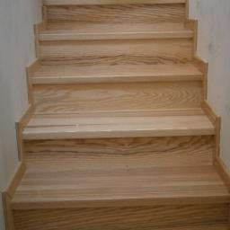 Eldrew - Jasne drewniane schody z widocznym usłojeniem, zamontowane przy białej ścianie, ujęcie od dołu.