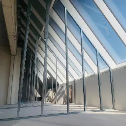 Konstrukcja metalowa pod skosny sufit z oknami dachowymi, widoczne płyty w tle, surowy beton na górze ściany, wnętrze w trakcie remontu.