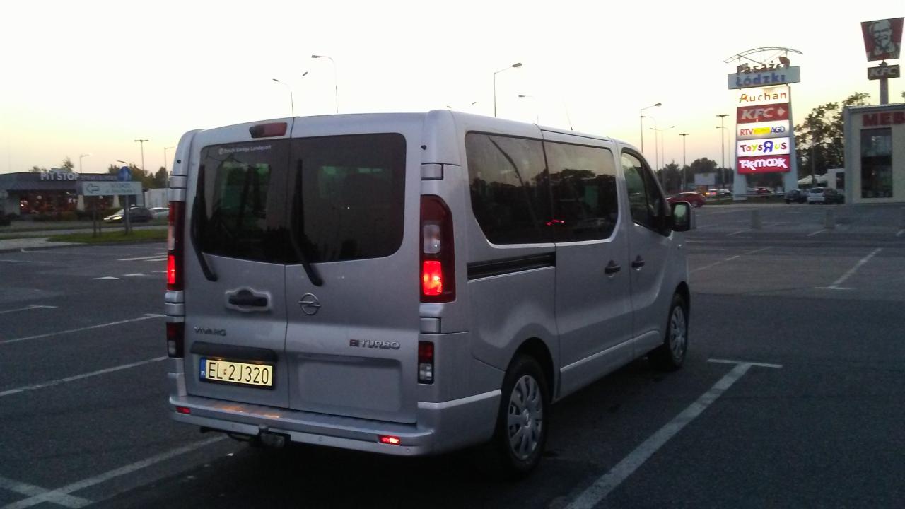 Srebrny Opel Vivaro BiTurbo zaparkowany na parkingu przed centrum handlowym Pasaz Łódzki o zmierzchu, widok z tyłu.