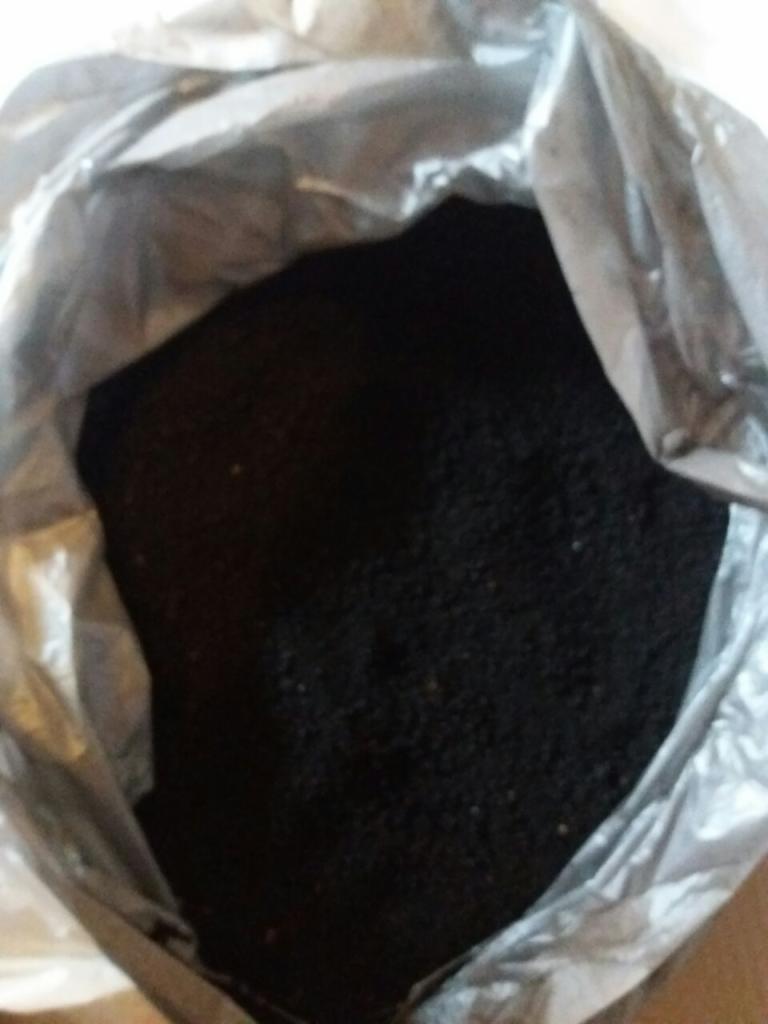 Worek wypełniony ciemnym, sypkim podłożem o grubej strukturze, widzianym z góry pod kątem.