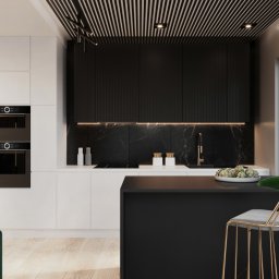 Osky Justyna Knapek - Nowoczesna kuchnia z czarnymi szafkami, marmurowym blatem, białą wyspą i złotym krzesłem barowym, oświetlona listwami LED pod szafkami.