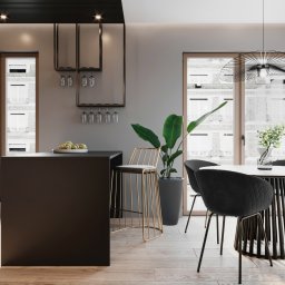 Osky Justyna Knapek - Nowoczesna jadalnia z okrągłym stołem, czarnymi krzesłami i złotym hokerem, minimalistyczna wyspa kuchenna z owocami, widok na miejski budynek przez okno.