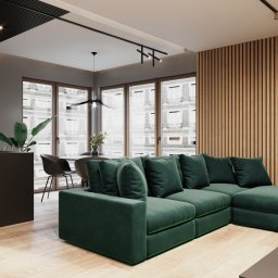 Osky Justyna Knapek - Wizualizacja wnętrza salonu z zieloną sofą narożną, drewnianą ścianą z pionowymi panelami i nowoczesnym oświetleniem sufitowym.
