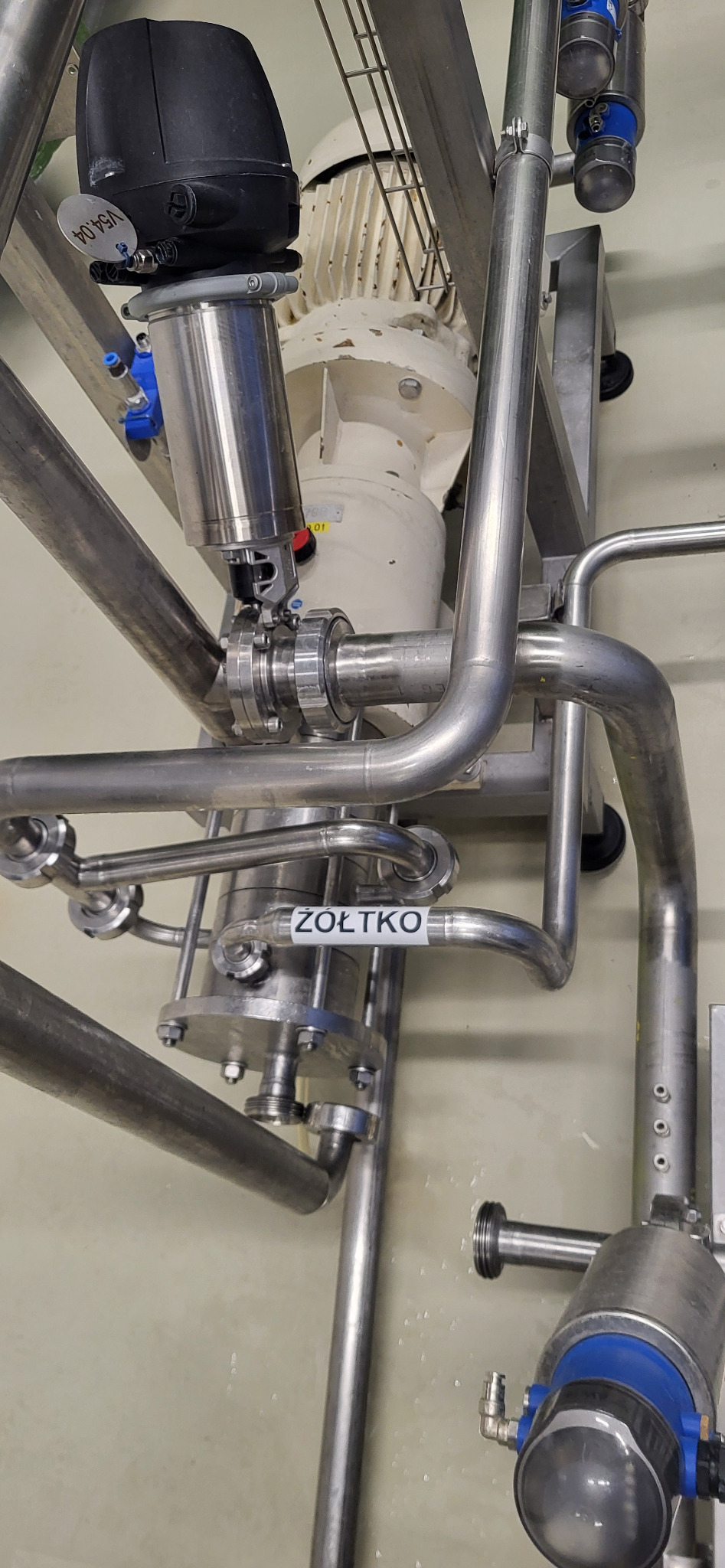 Kompleksowa instalacja przemysłowa z rur ze stali nierdzewnej, z widocznym silnikiem i elementami sterującymi, oznaczona etykietą 'ŻÓŁTKO'.
