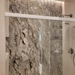 Wykończona kabina prysznicowa z marmurową ścianą w Tczewie. Szklane drzwi przesuwne, oświetlenie LED i nowoczesna armatura. Elegancki design łazienki.