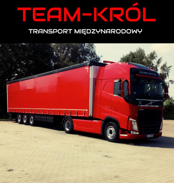 Czerwona ciężarówka Volvo z naczepą, zaparkowana na placu z kostki brukowej, z napisem 'TEAM-KRÓL TRANSPORT MIĘDZYNARODOWY' u góry zdjęcia.