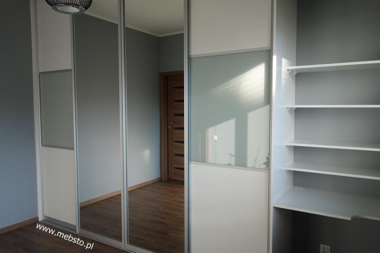 Nowoczesna szafa wnękowa z przesuwnymi drzwiami z lustrami i matowym szkłem, wbudowana w szarą ścianę, z otwartymi półkami po prawej stronie.