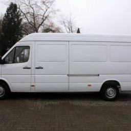 Lider-Trans - Biały, dostawczy van marki Mercedes-Benz Sprinter z wysokim dachem, zaparkowany na brukowanej powierzchni, widok z boku na tle drzew i budynków.